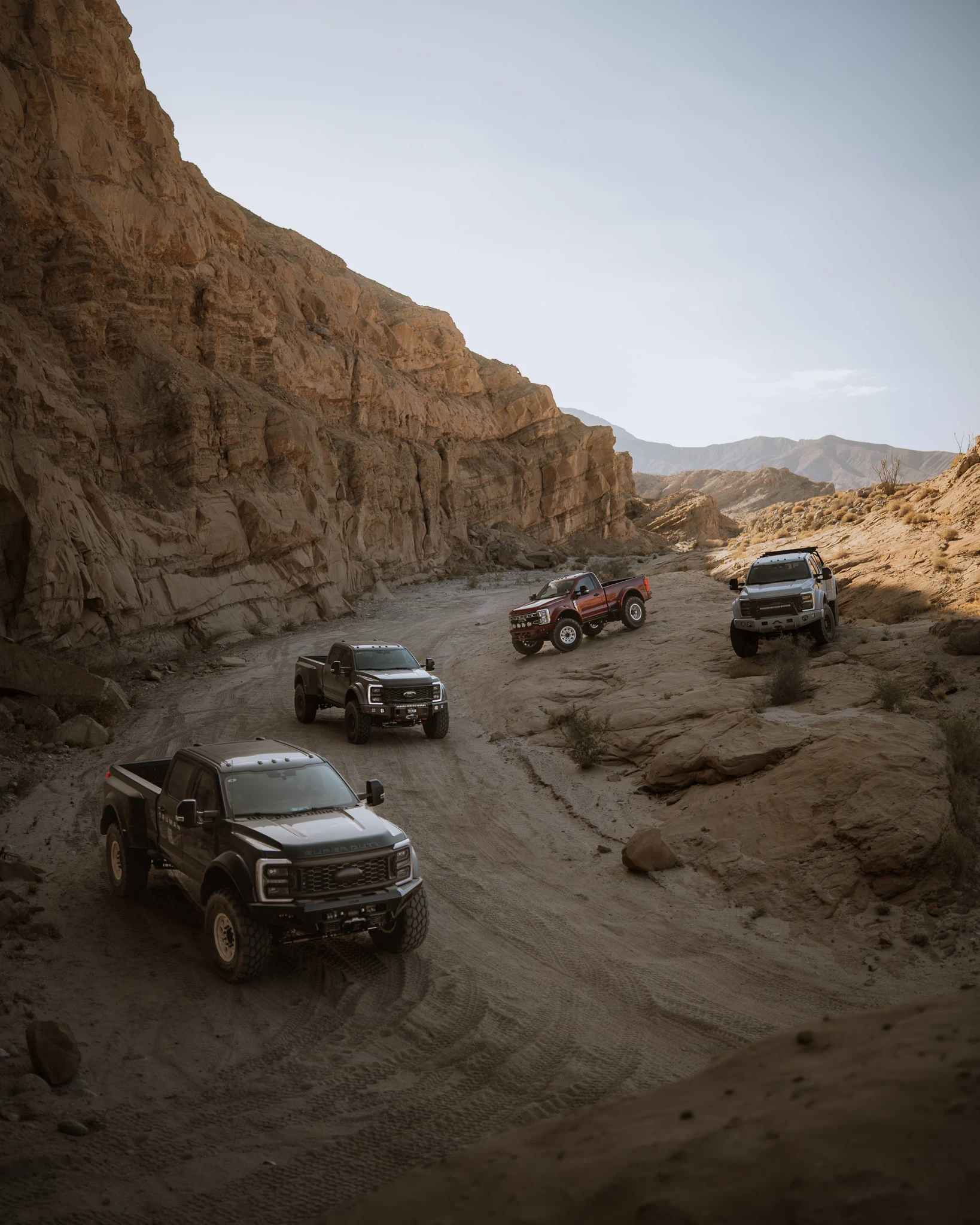 Four Truman trucks exploring a rugged desert canyon